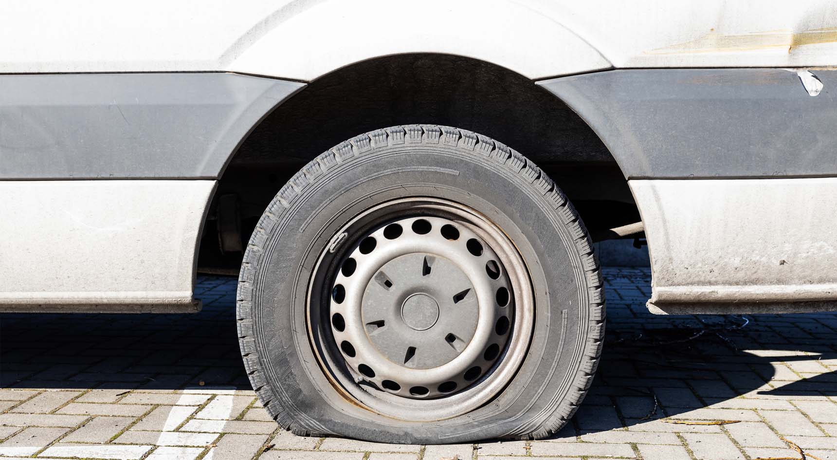 A car in the driveway with a flat tyre