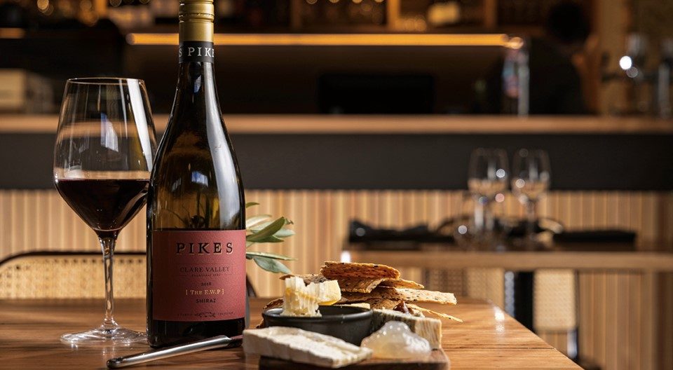 Bottle of Pikes wine with a glass and cheese platter