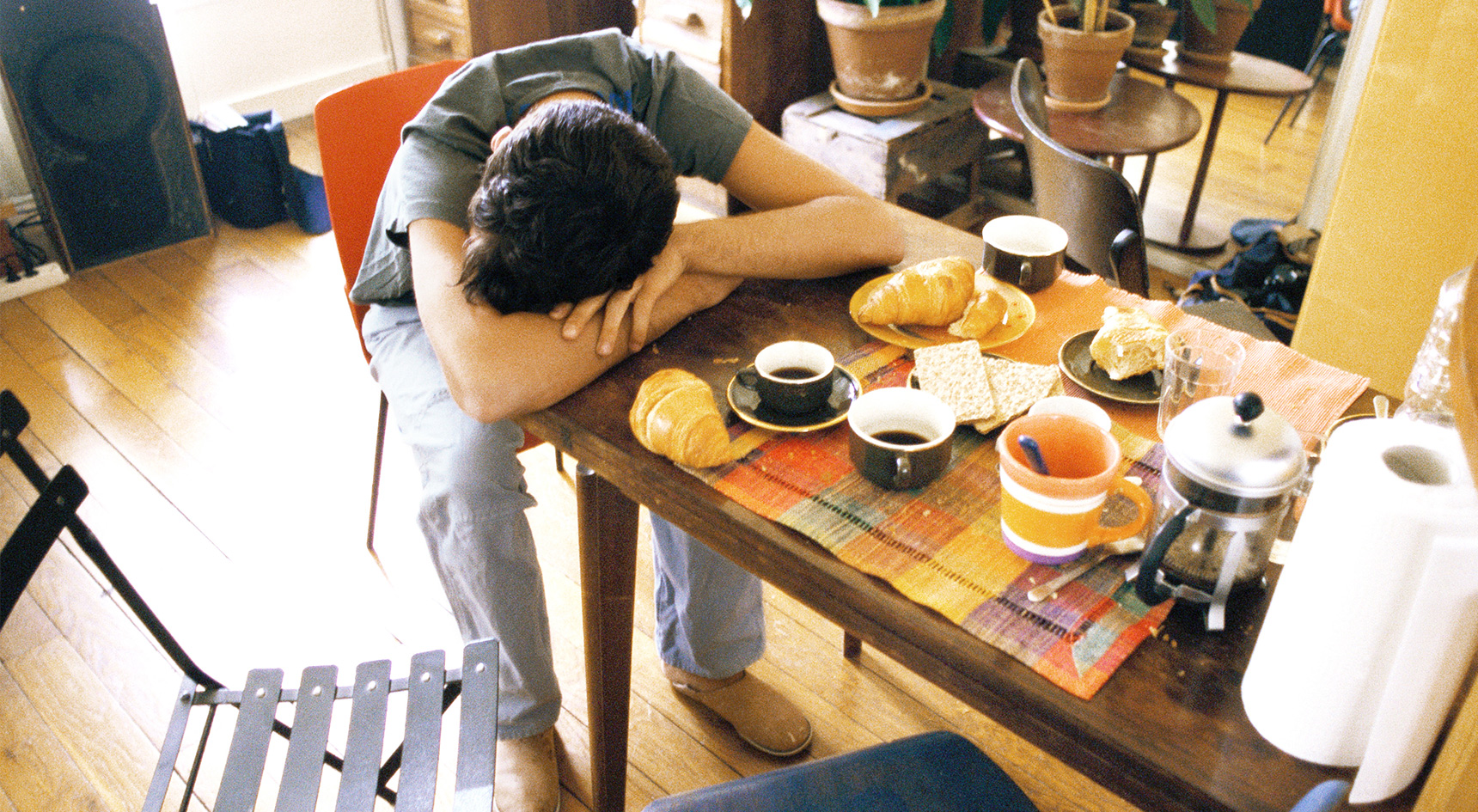 Man sleeping on a table in front of his breakfast