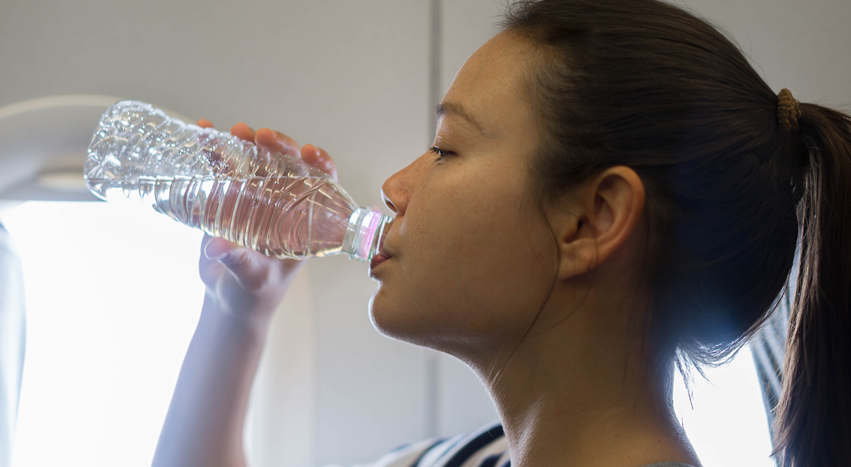 Female passenger drinking water on a plane