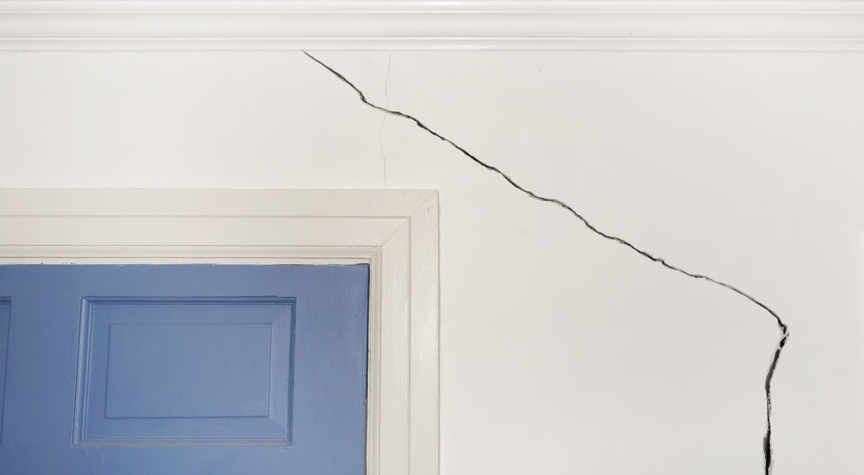 Crack in a wall above blue door