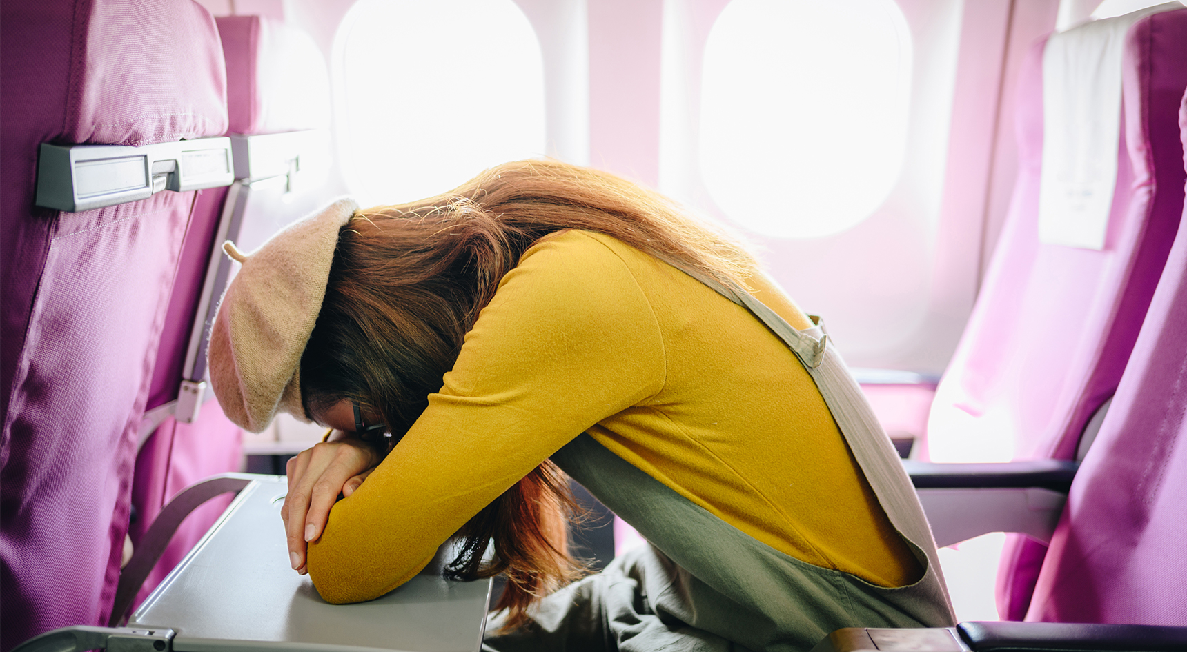 Woman lying forward to sleep on a plane