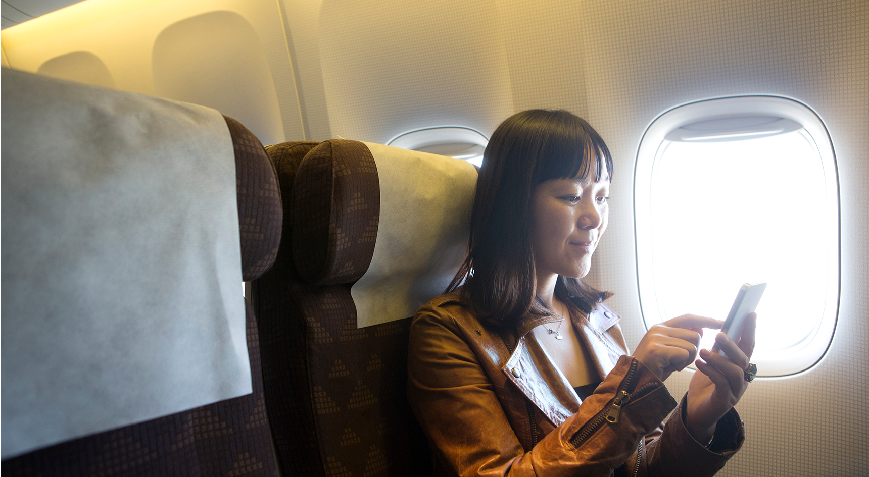 Woman looking at smartphone on a plane