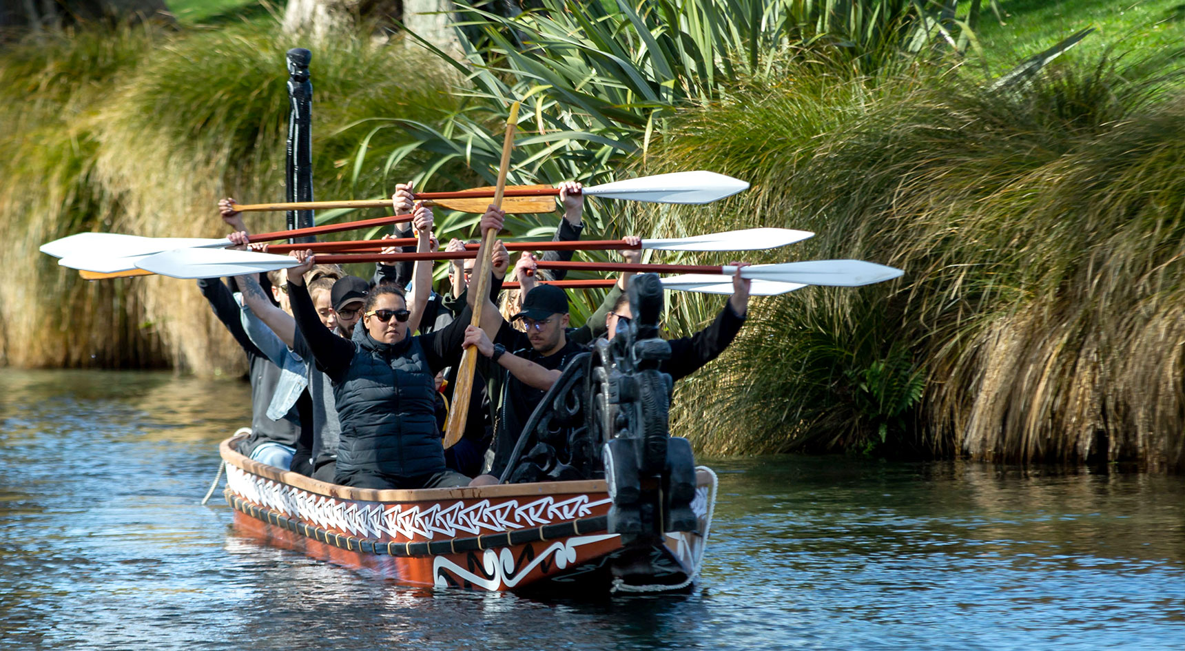 A group of people holding oars in a traditional canoe