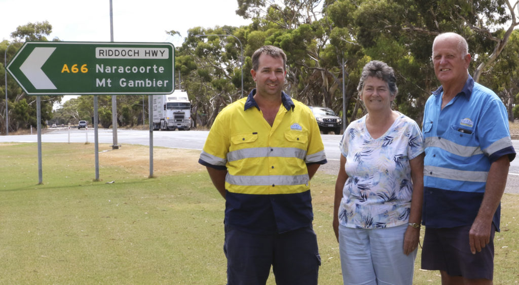 Norton Harvesters owner Chris Norton (left) with parents Jennifer and Kerry Norton in front of the Riddoch Highway turnoff to Naracoorte and Mount Gambier.