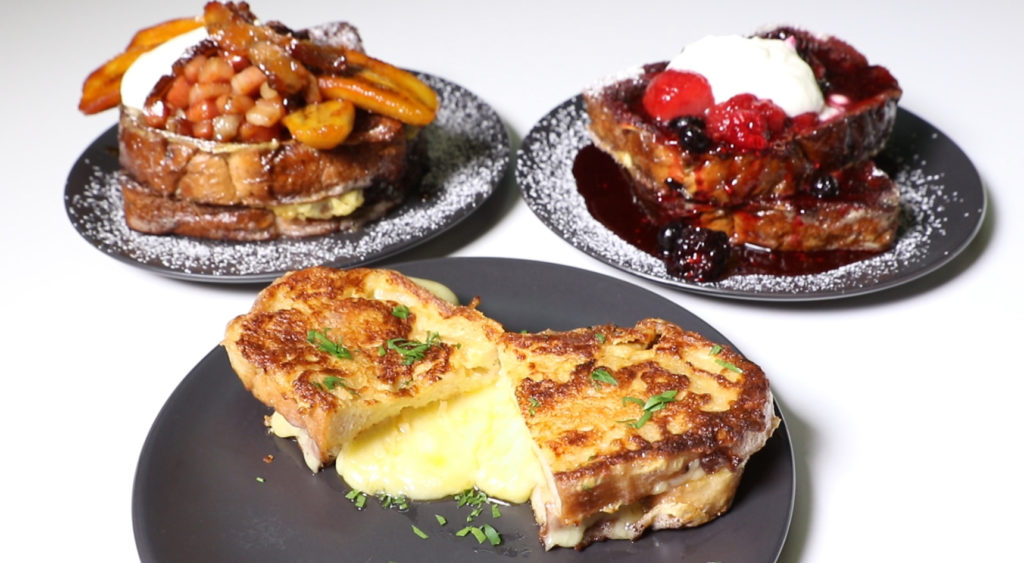 Three plates with French toast on them. One with bananas and maple syrup, another with cheese and the third with berries and yoghurt.