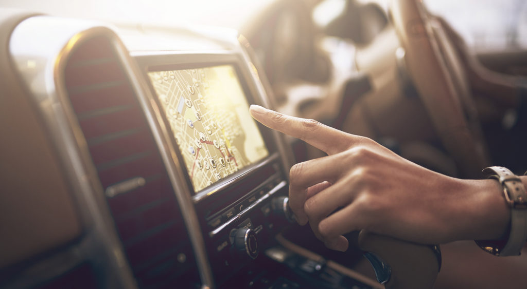 A left hand clicking on a GPS interface inside a car.