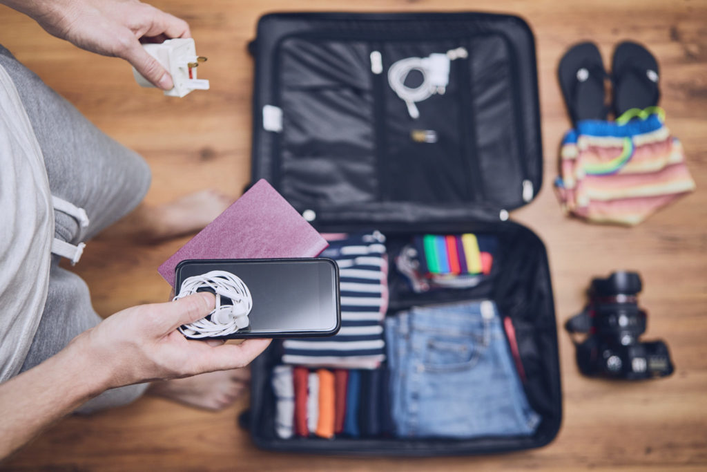 Man packing phone charger into suitcase