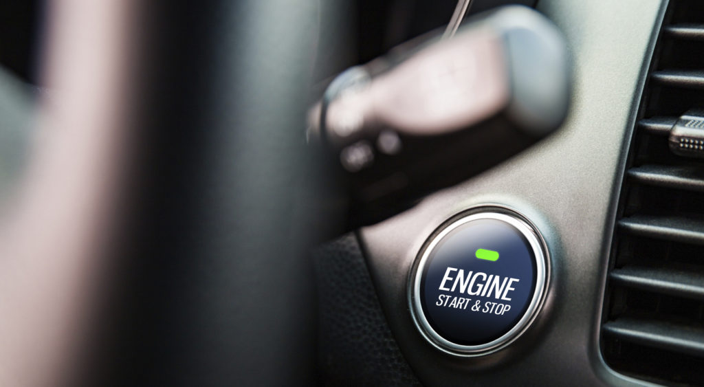 Push-button ignition in the background and a blurred steering wheel and indicator stick in the foreground.