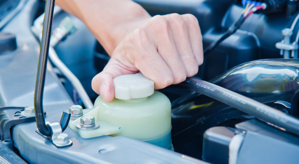 A hand tightening the lid for the coolant reservoir.