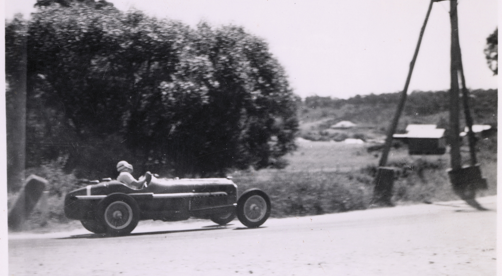 Historic image of a race car speeding through the Adelaide Hills as it competes in the 1939 Australian Grand Prix.