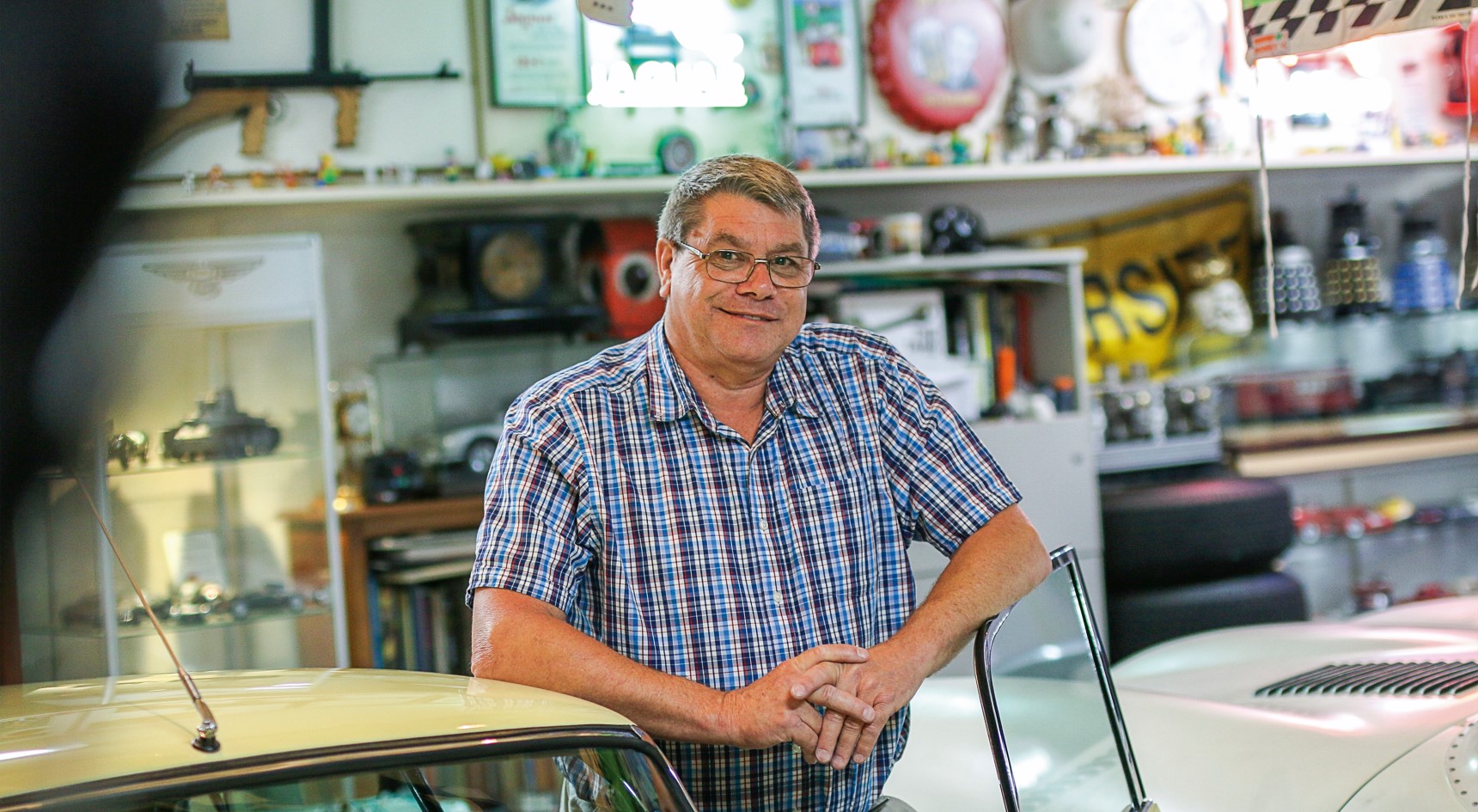 Alan Baker in his garage, leaning on one of his cars. Image: Ellen Morgan