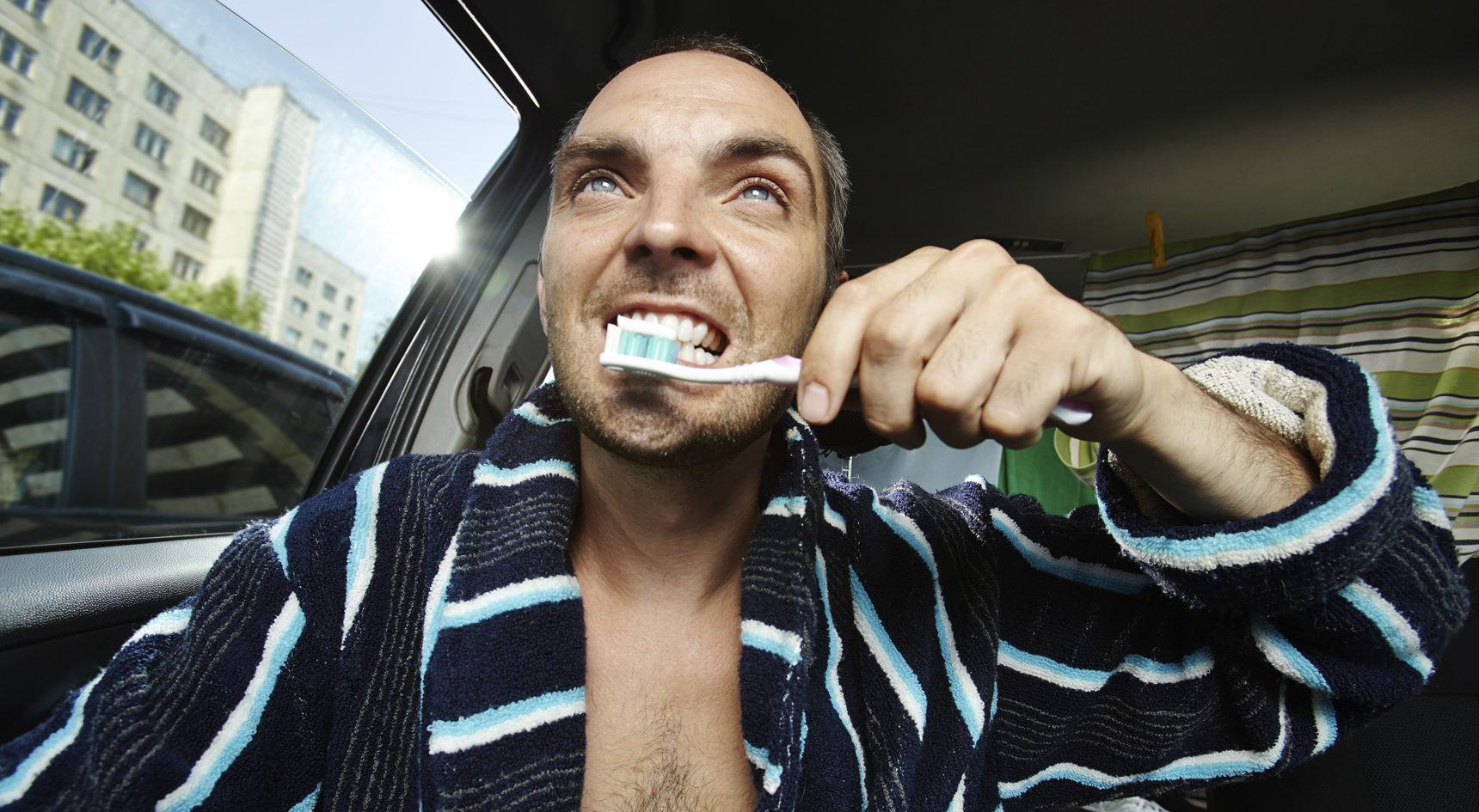 Man brushing his teeth while driving.