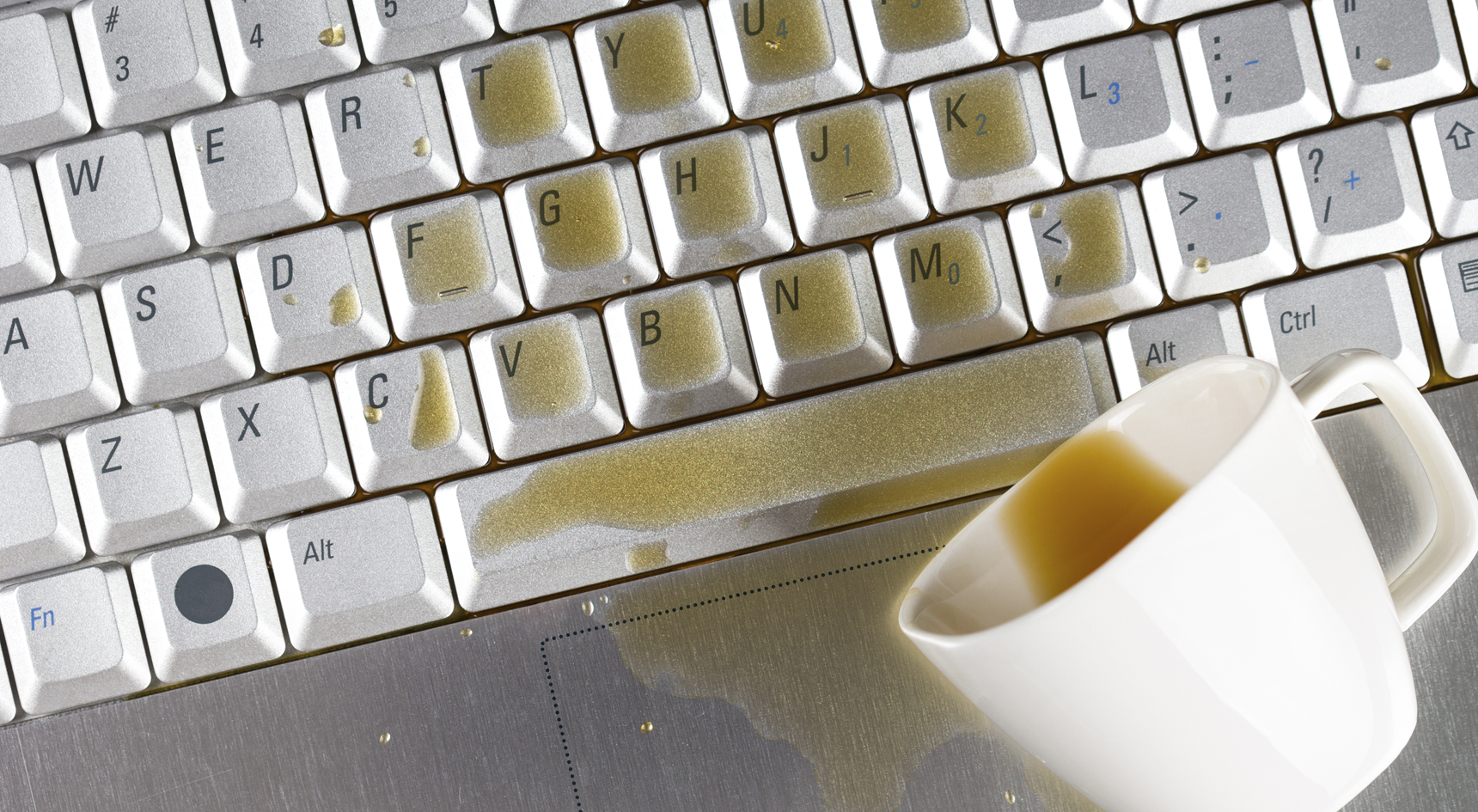 A coffee cup spilled on a laptop.
