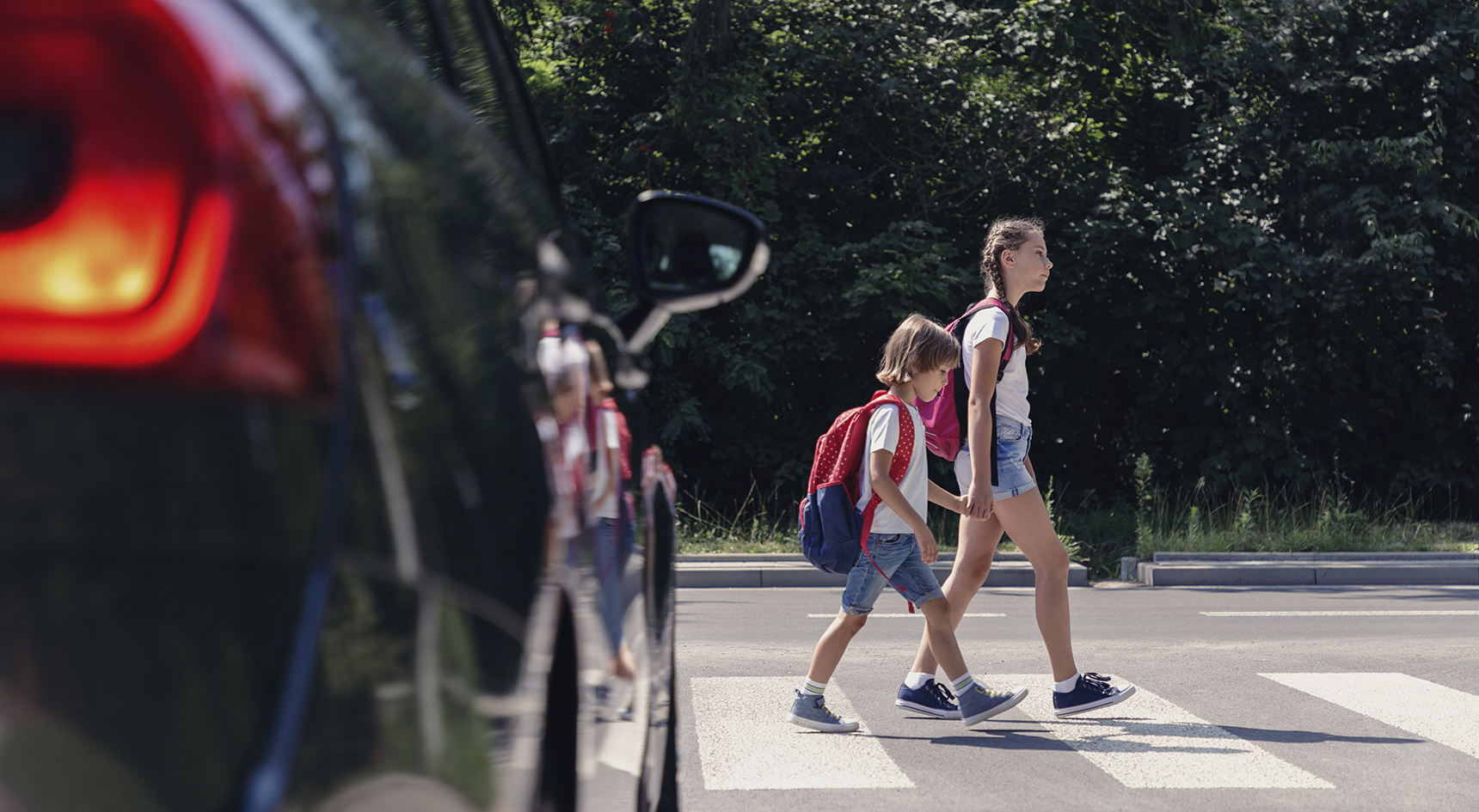 Children crossing a school crossing as a car waits