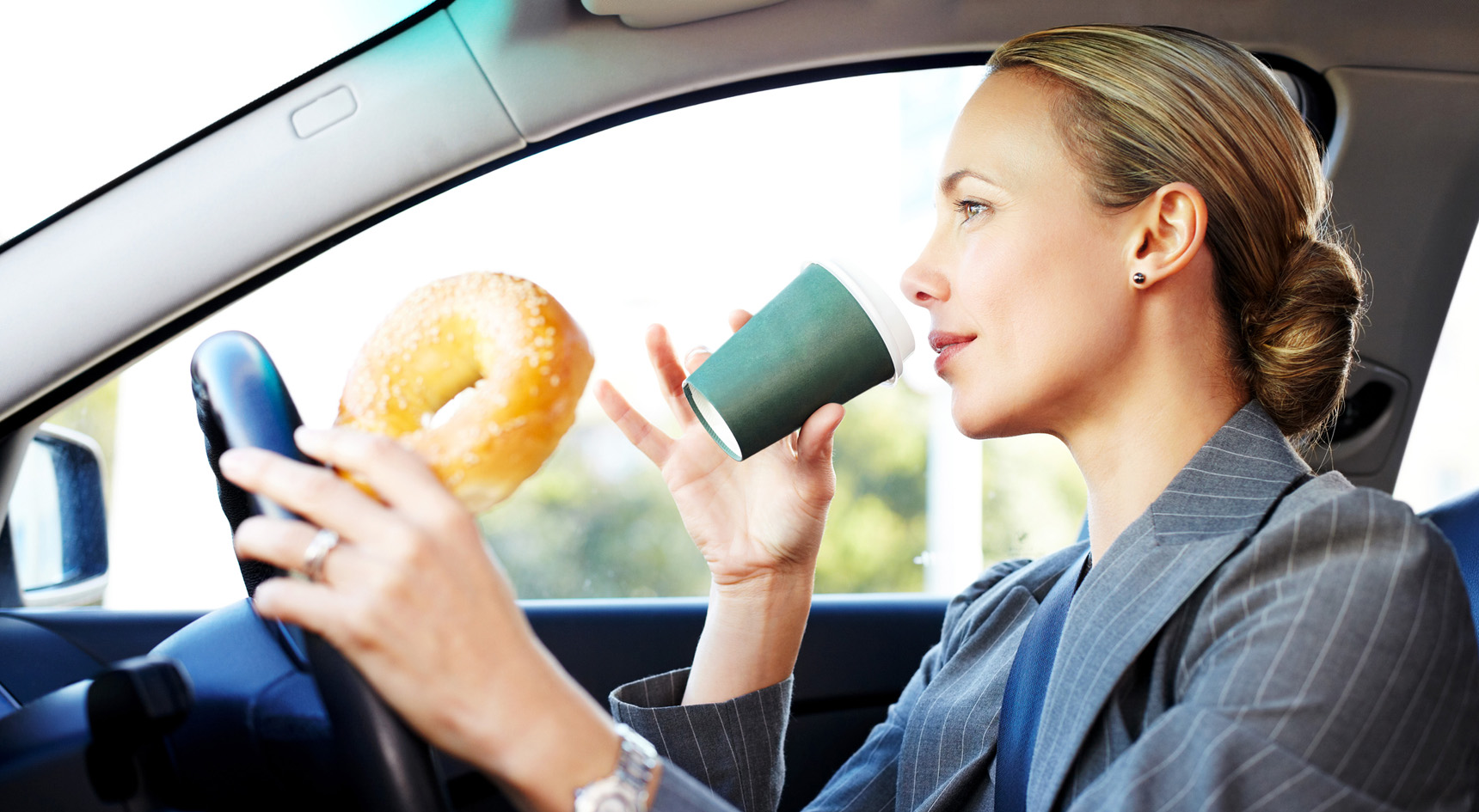 Woman eating and drinking while driving. Image: Getty.