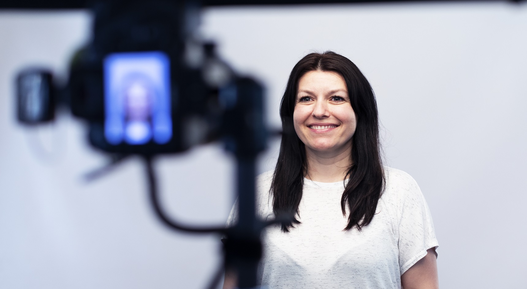 Woman smiling in front of camera lens.