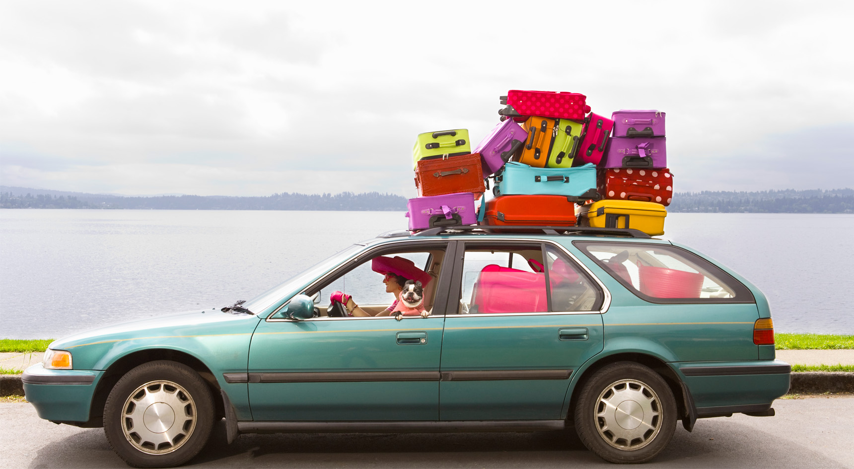 Luggage piled on car roof.