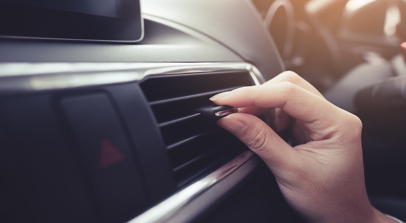 Close-up of female hand adjusting air ventilation grille .