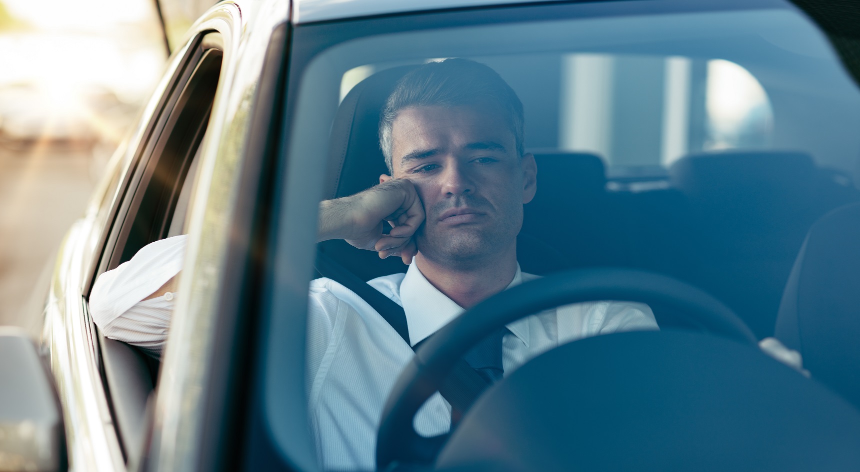 Man sitting in car, looking bored.