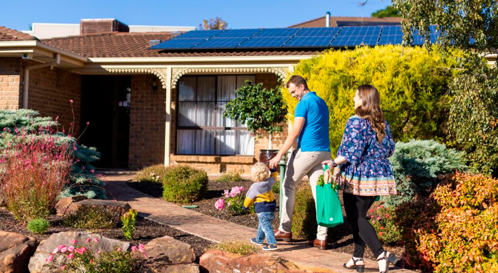 Family walking into house with solar panels on the roof. Image: RAA.