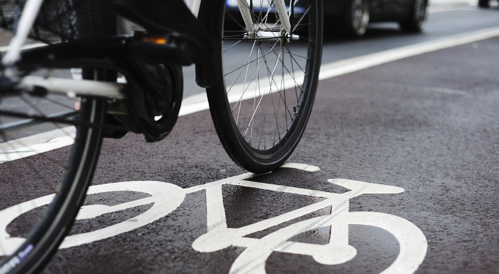 A bicyclist riding through a bike line with cars in the background.