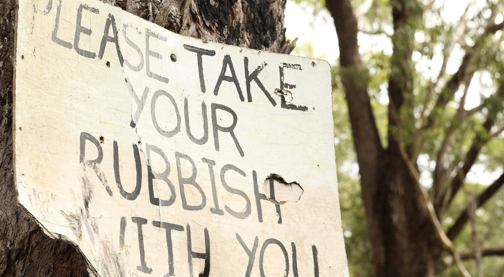 A sign at a camping site that says 'Please take your rubbish with you',