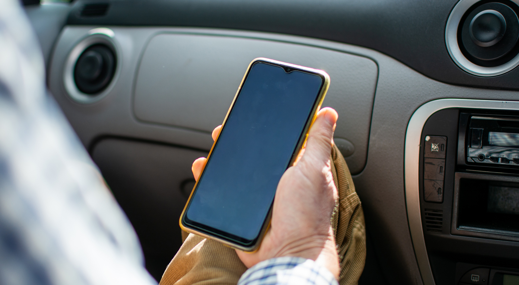 A passenger in a car using their mobile phone.