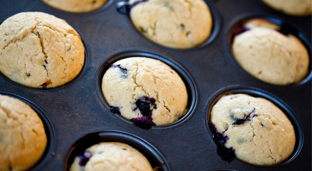 Close-up of blueberry muffins in a baking tray, fresh out of the oven.
