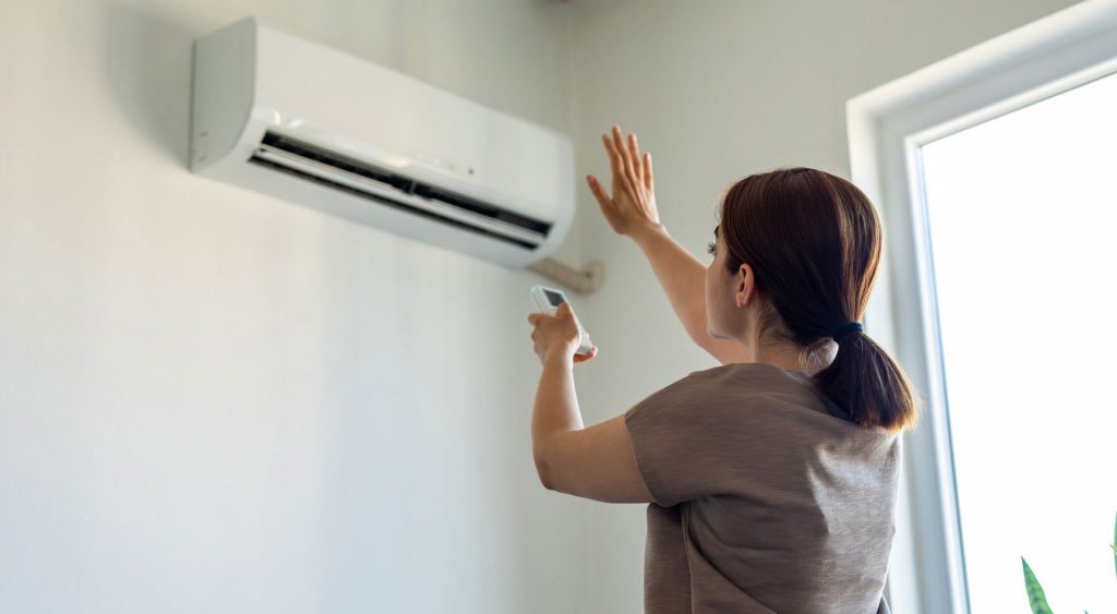 A person switching on the air-con and checking that it's circulating cool air.