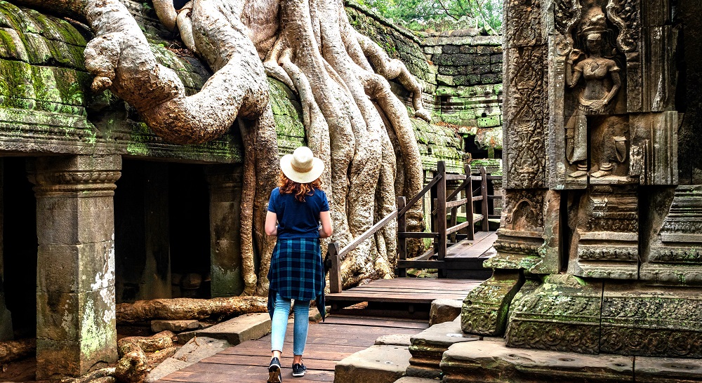 A person walking through Ta Prohm Temple in Cambodia.