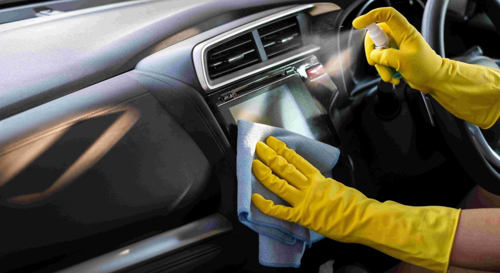 Worker cleaning car dashboard.