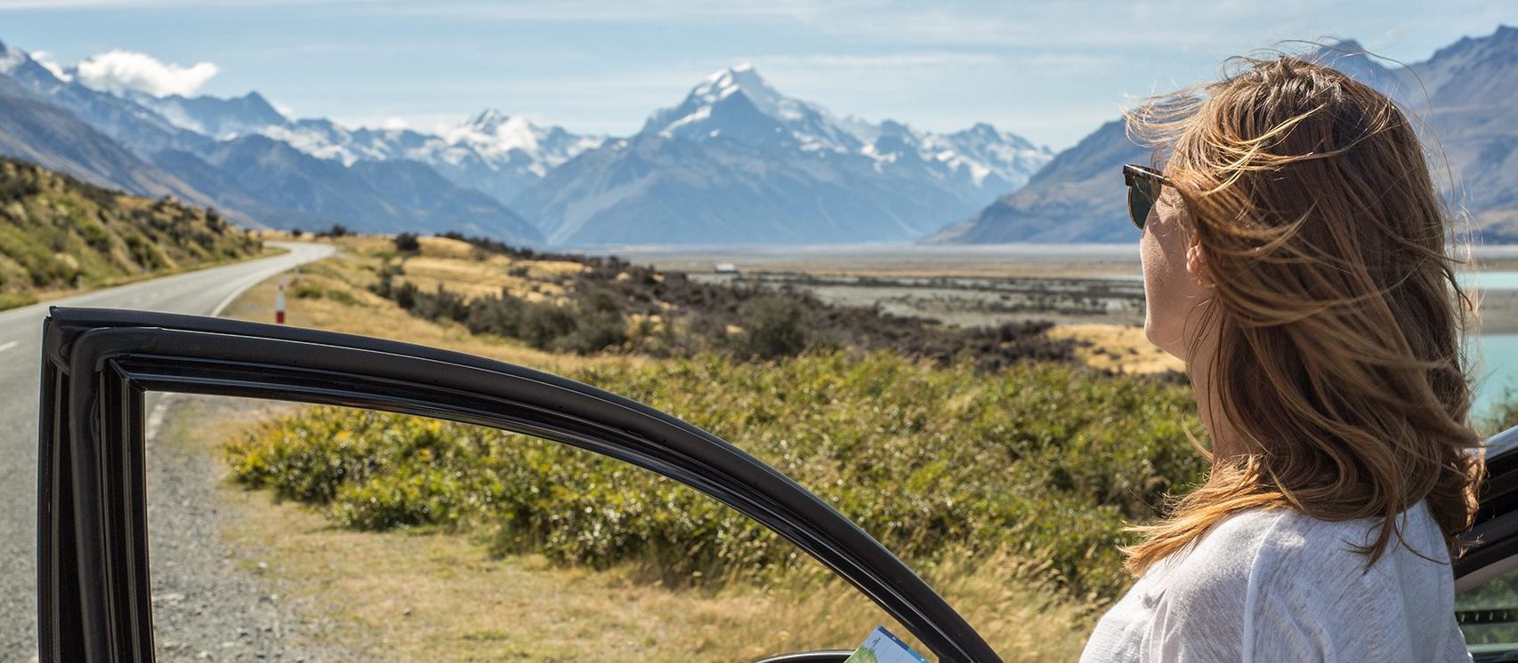 Woman standing out of car looking at map, Mount Cook