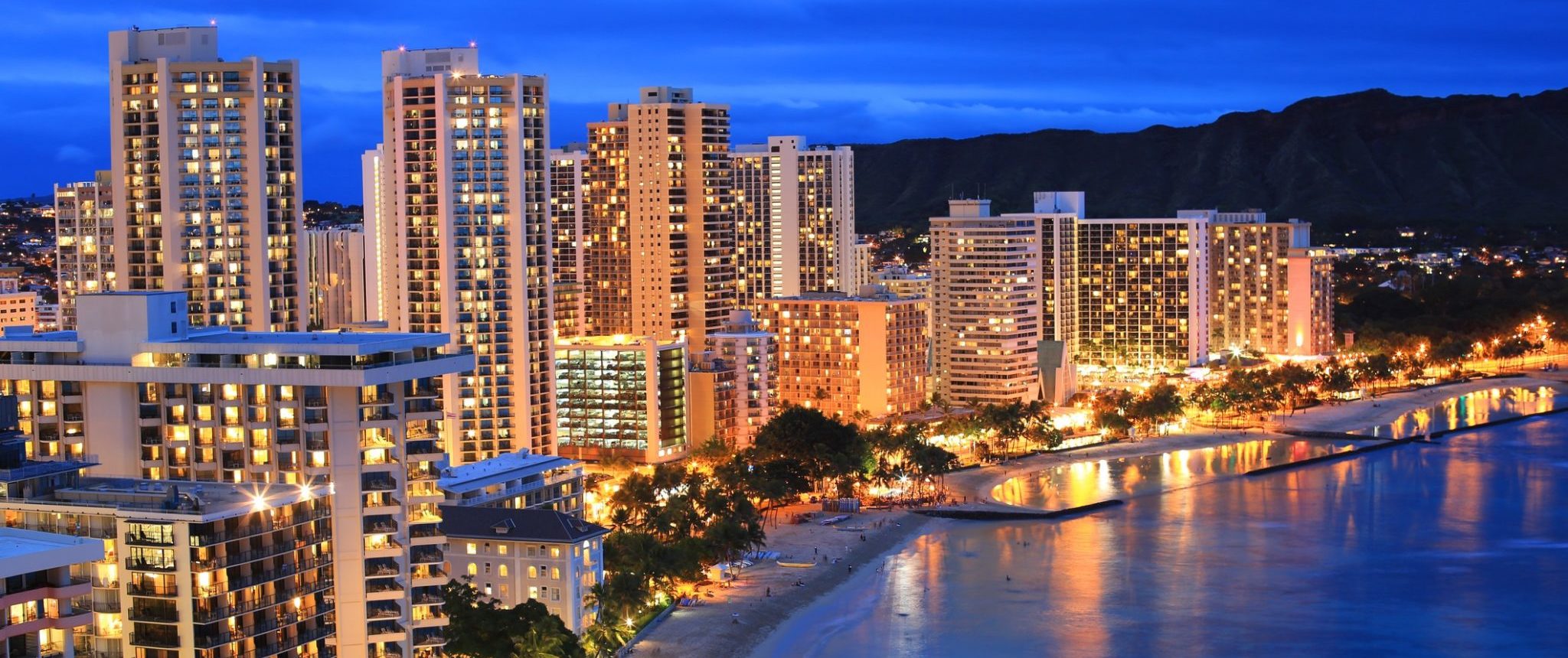 Waikiki Beach with buildings lit up at night.