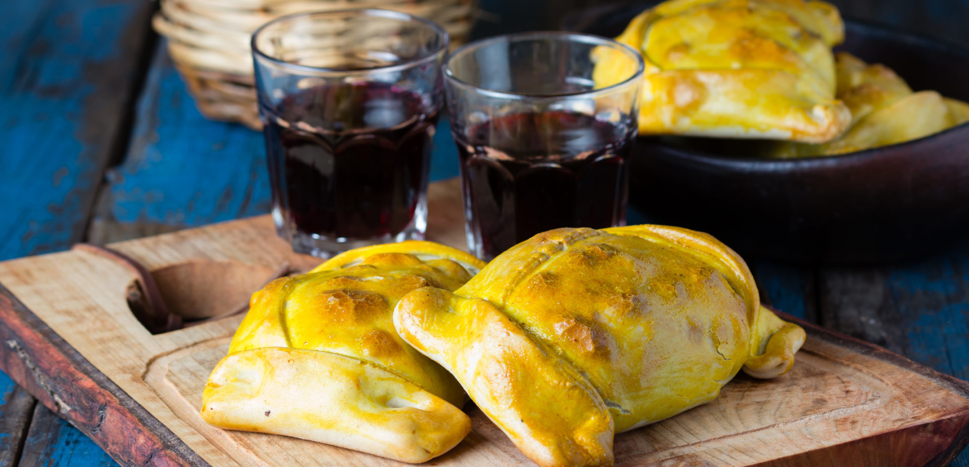 Empanadas on a plate with a glass of wine.